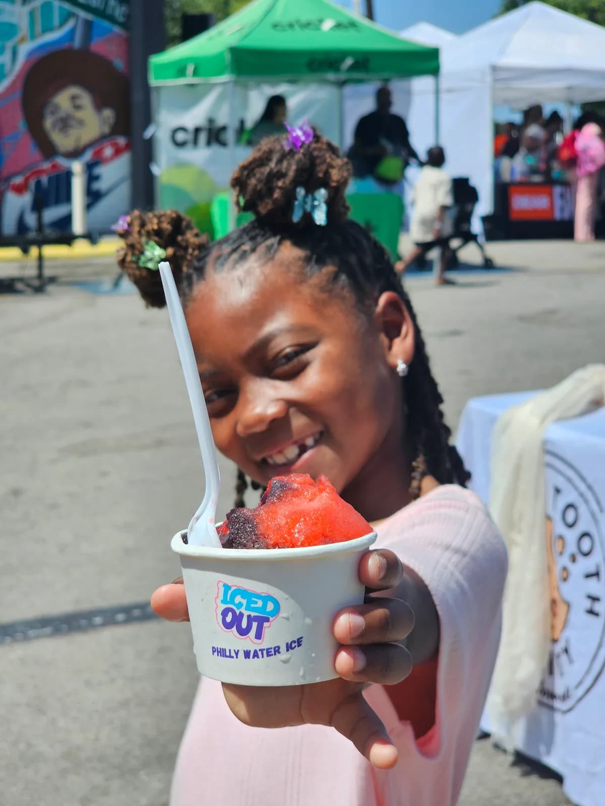 A girl smiling with her Iced Out water ice at a Dear Fathers back-to-school event