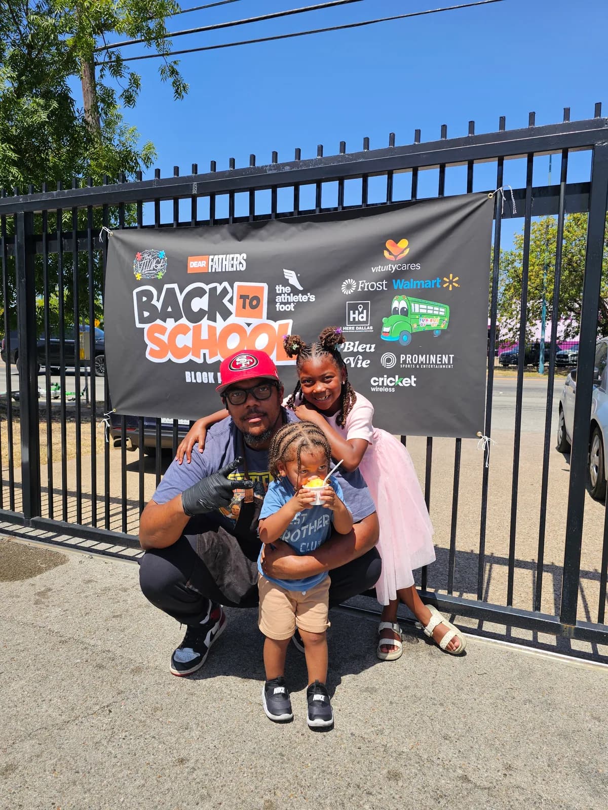 A father and two children posing together at a Dear Fathers back-to-school event