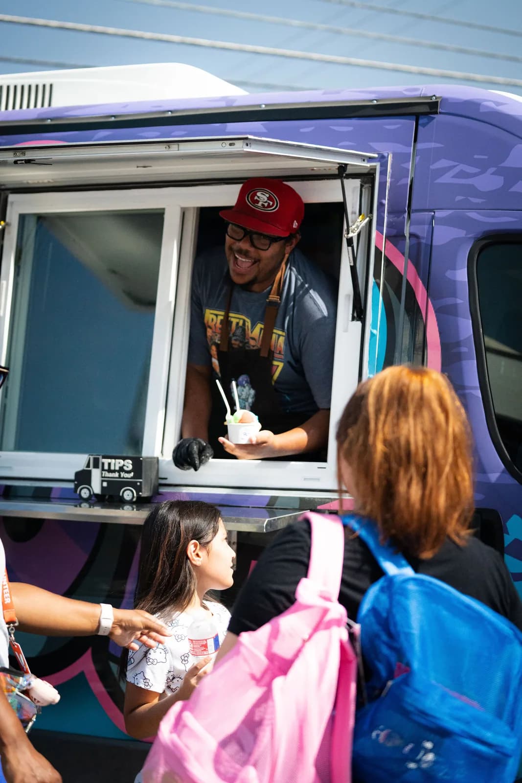 An Iced Out team member serving water ice to families at a Dear Fathers event