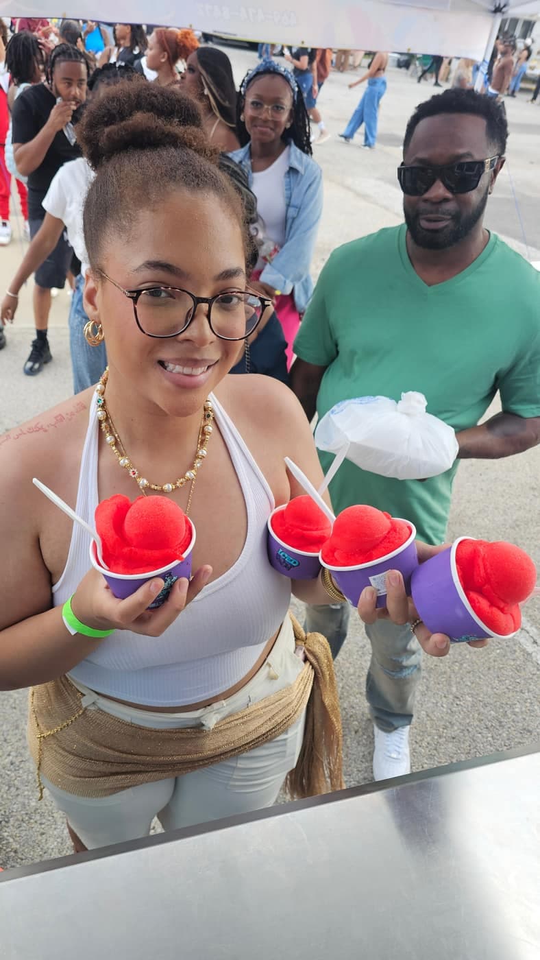 Guests holding colorful cups of Iced Out water ice with a line behind them