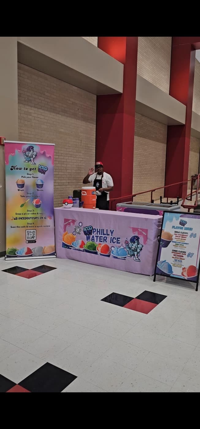 Iced Out Philly Water Ice scoop bar booth set up indoors with flavor menu and staff serving